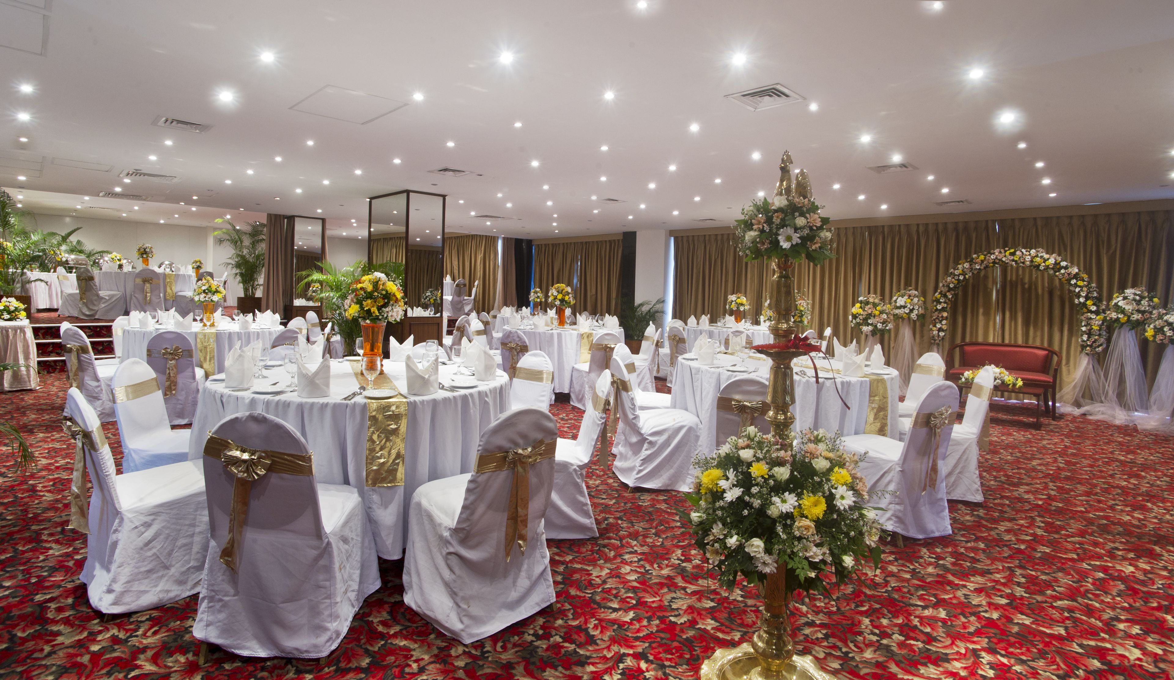 A banquet hall with round tables, white tablecloths, and gold sashes.