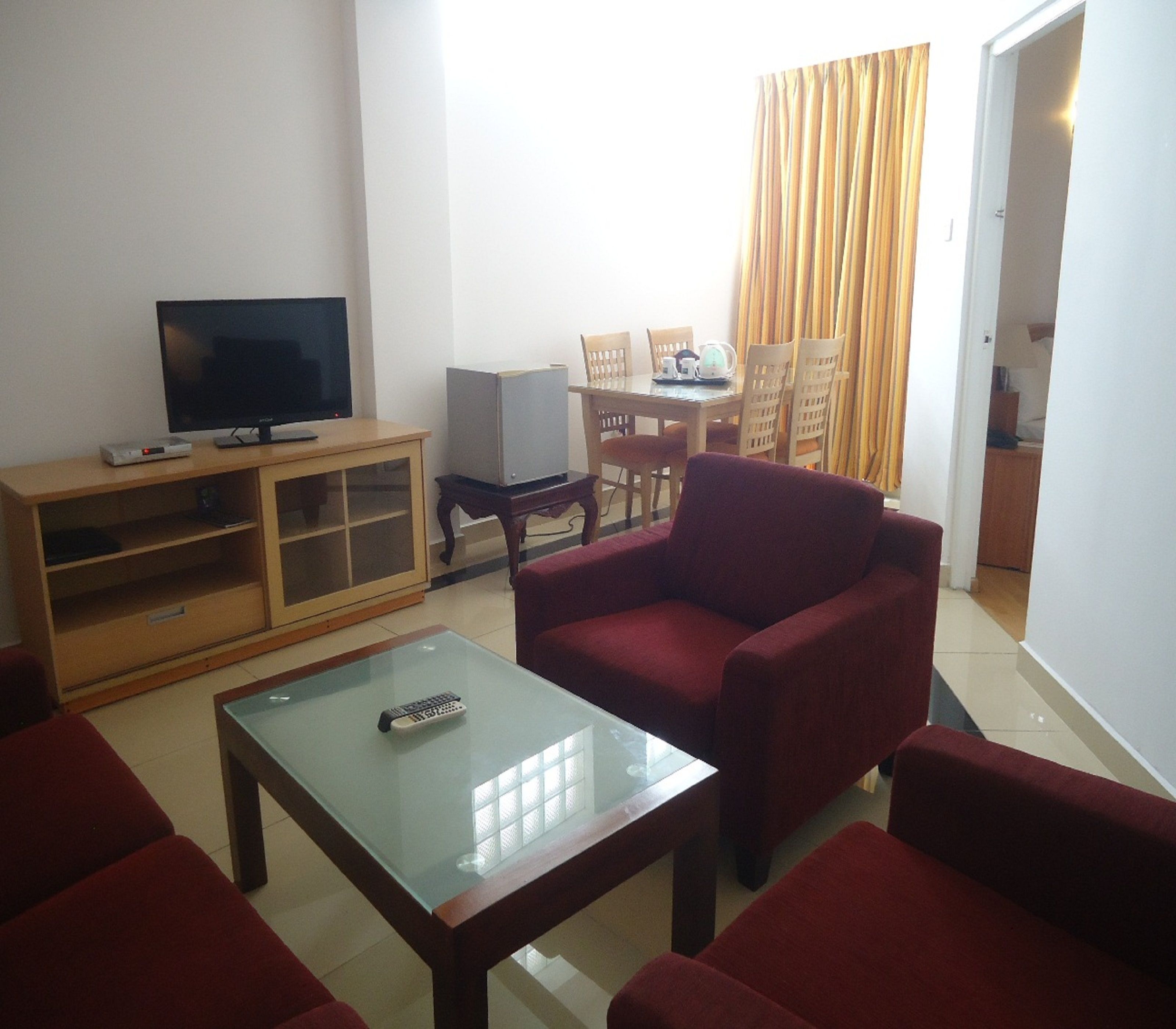 A living room with a television, a small table, and red furniture.