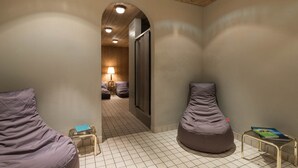 A room with two bean bags, a small table with a book, and a lamp in the background. - Boutique Hotel Am Park (Valdaora)