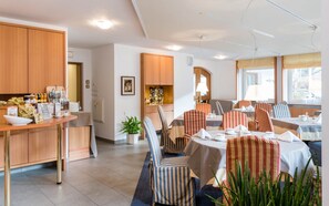 Un espace repas avec des chaises à rayures, une table de buffet et des meubles de rangement en bois.