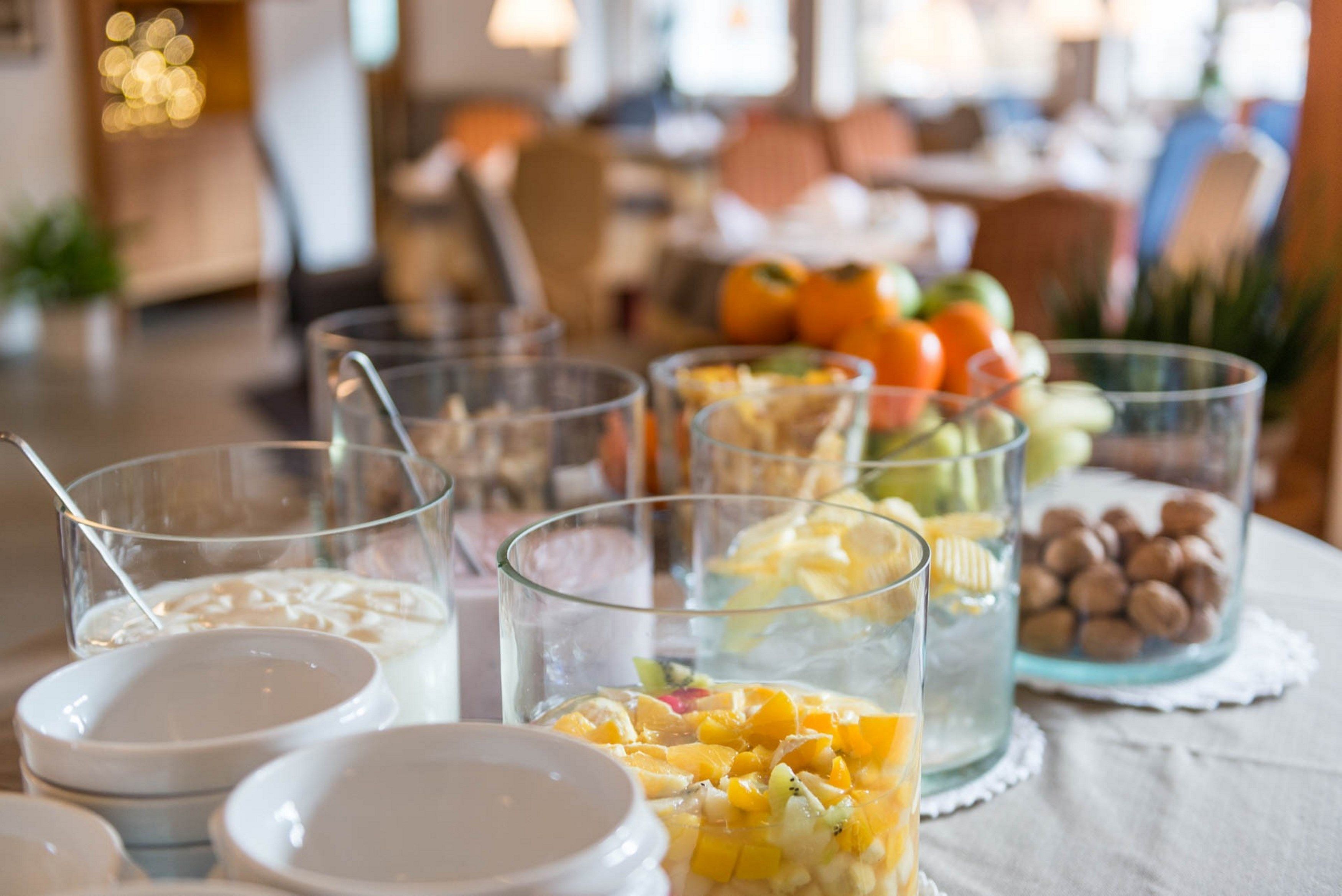 Una mesa con diversos alimentos y bebidas, incluyendo tazones de cereal, vasos de leche y un vaso con fruta mixta.