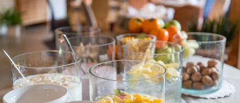 Una mesa con diversos alimentos y bebidas, incluyendo tazones de cereal, vasos de leche y un vaso con fruta mixta.