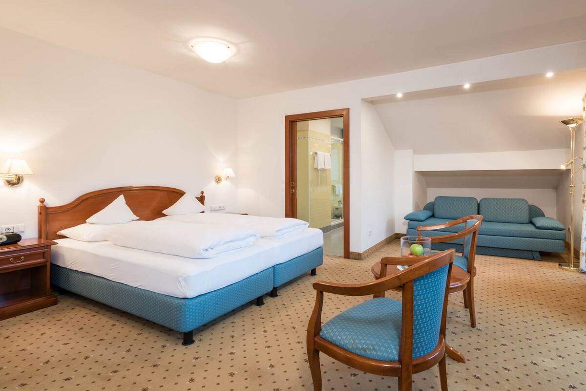 Ein Hotelzimmer mit einem Bett, einem Sessel, einer Couch und einem kleinen Tisch mit einer Lampe.