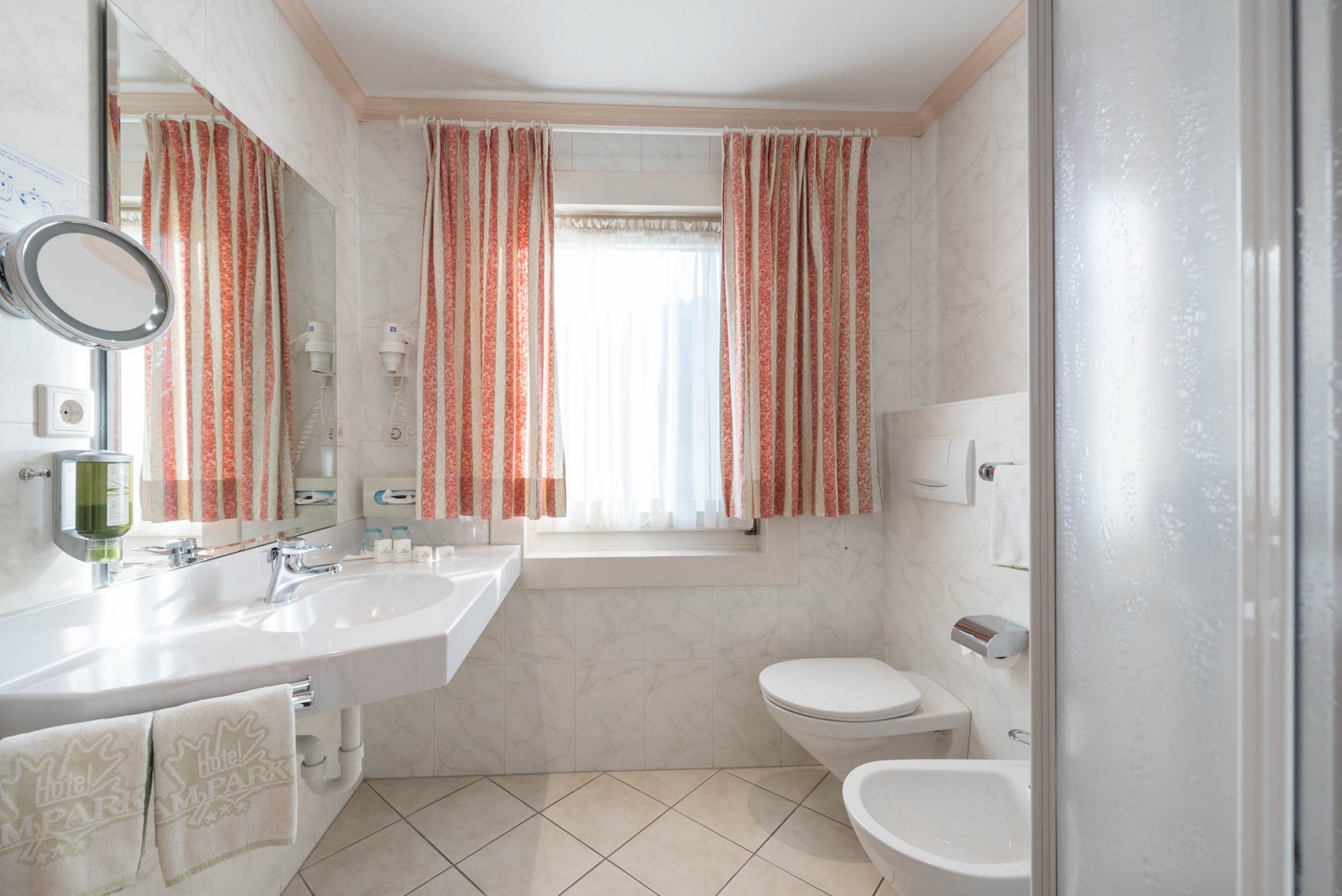 A modern bathroom with a sink, mirror, toilet, and bidet.