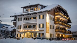 A multi-story hotel with balconies and a snow-covered roof. - Boutique Hotel Am Park (Valdaora)