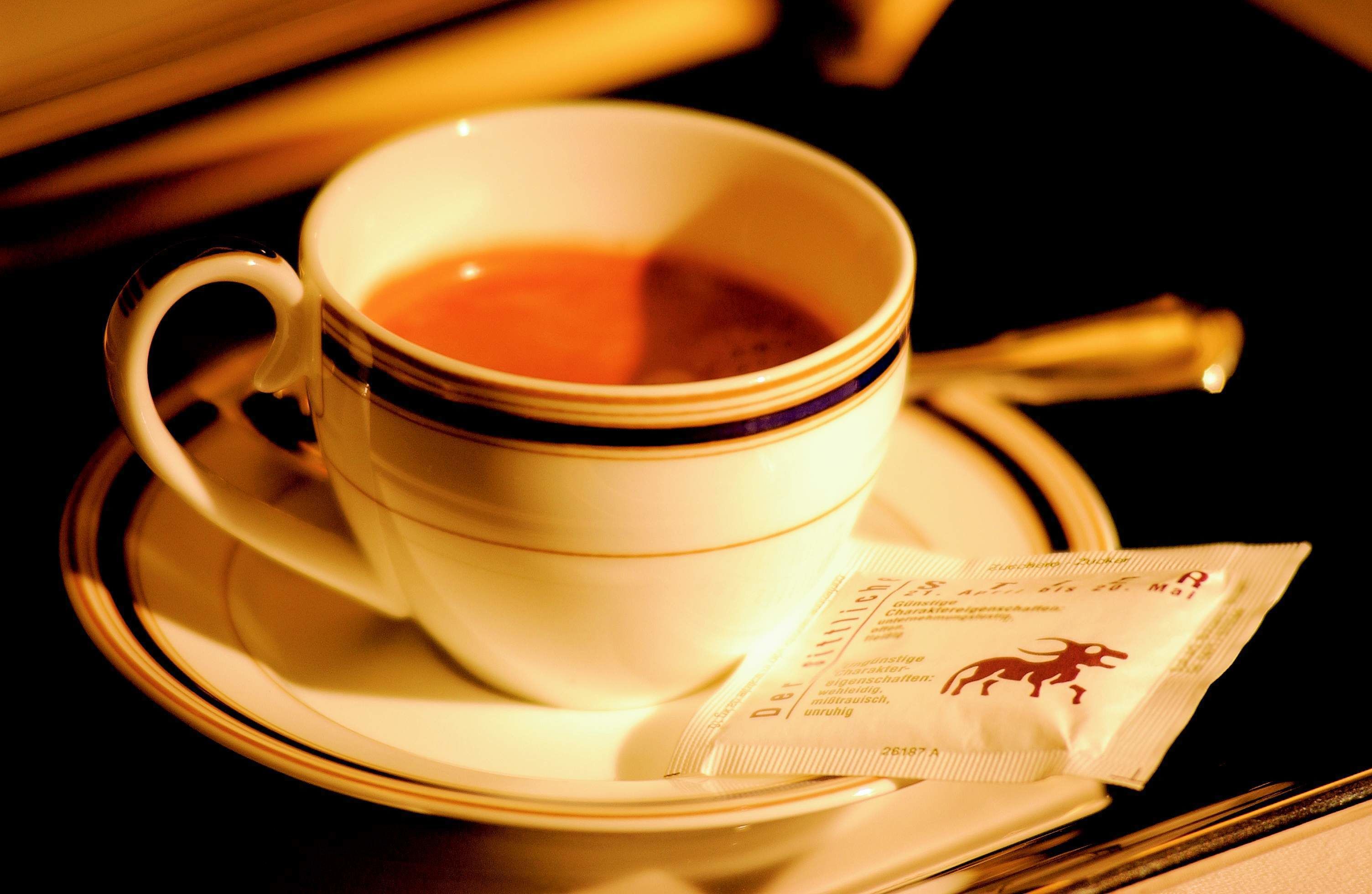 Una taza de té con un platito y sobres de té.
