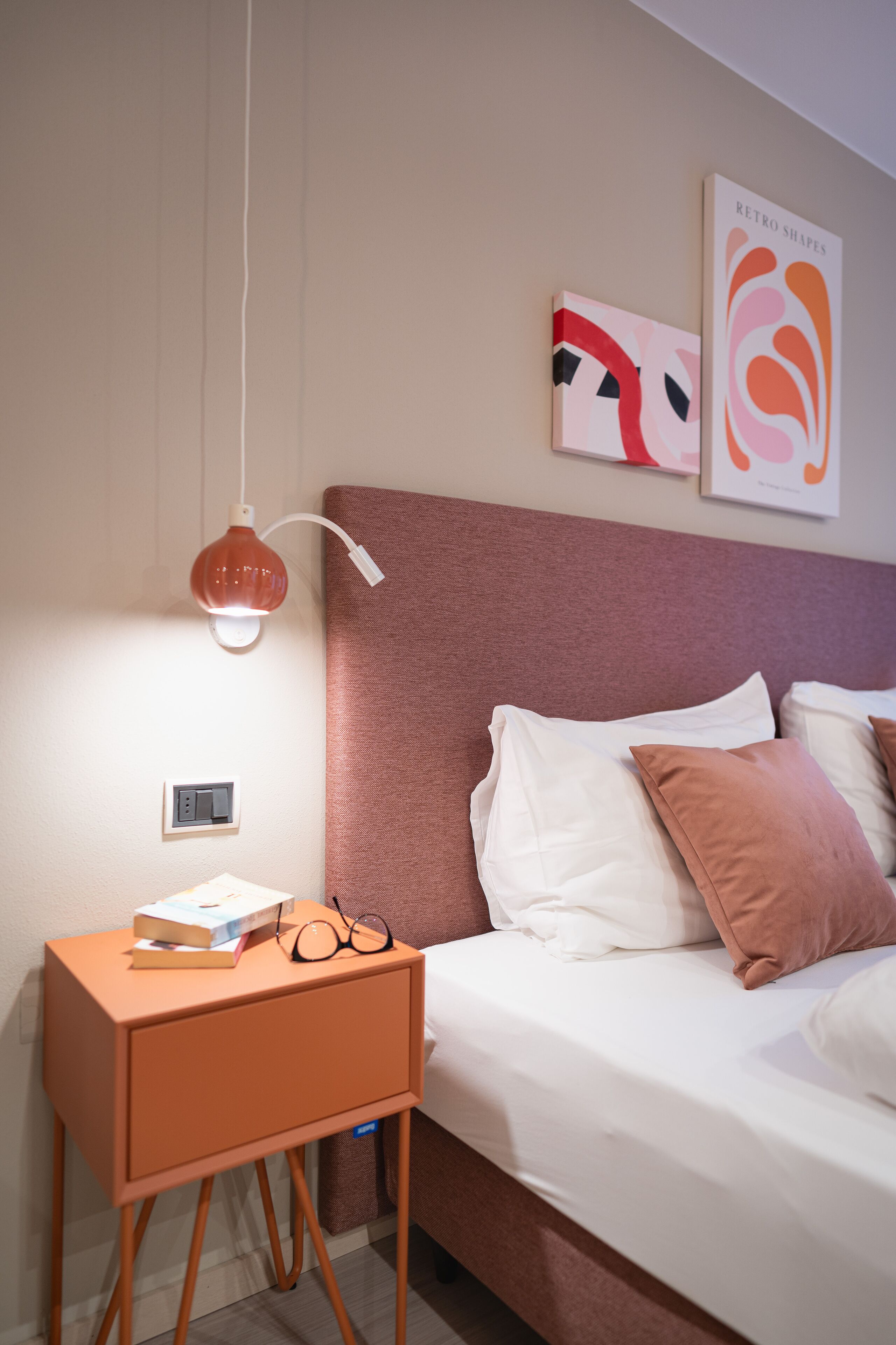 A neatly arranged bedroom with a bed, bedside table, and wall art.