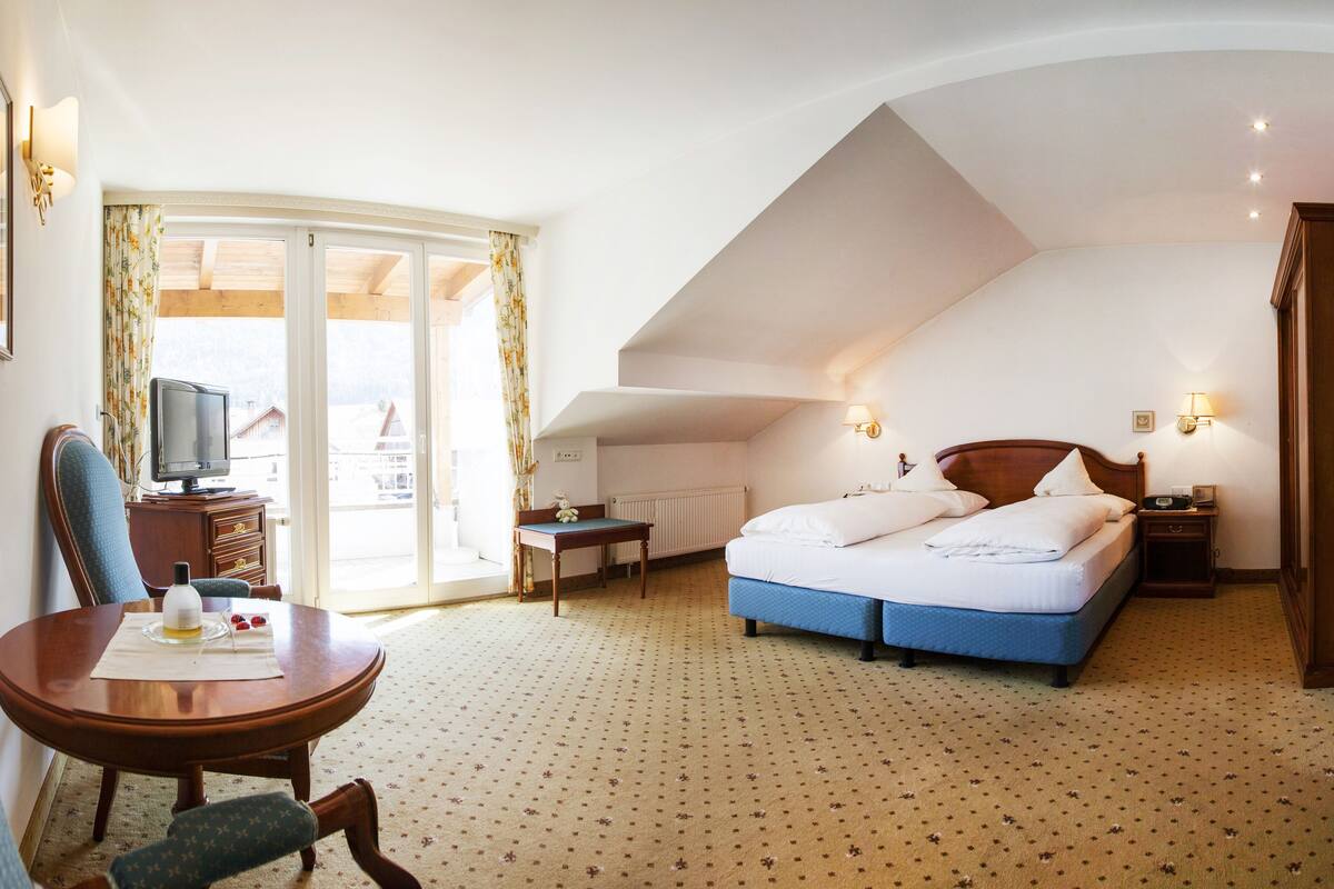 Ein Hotelzimmer mit Bett, Schreibtisch mit Stuhl, Fernseher und Blick ins Freie.