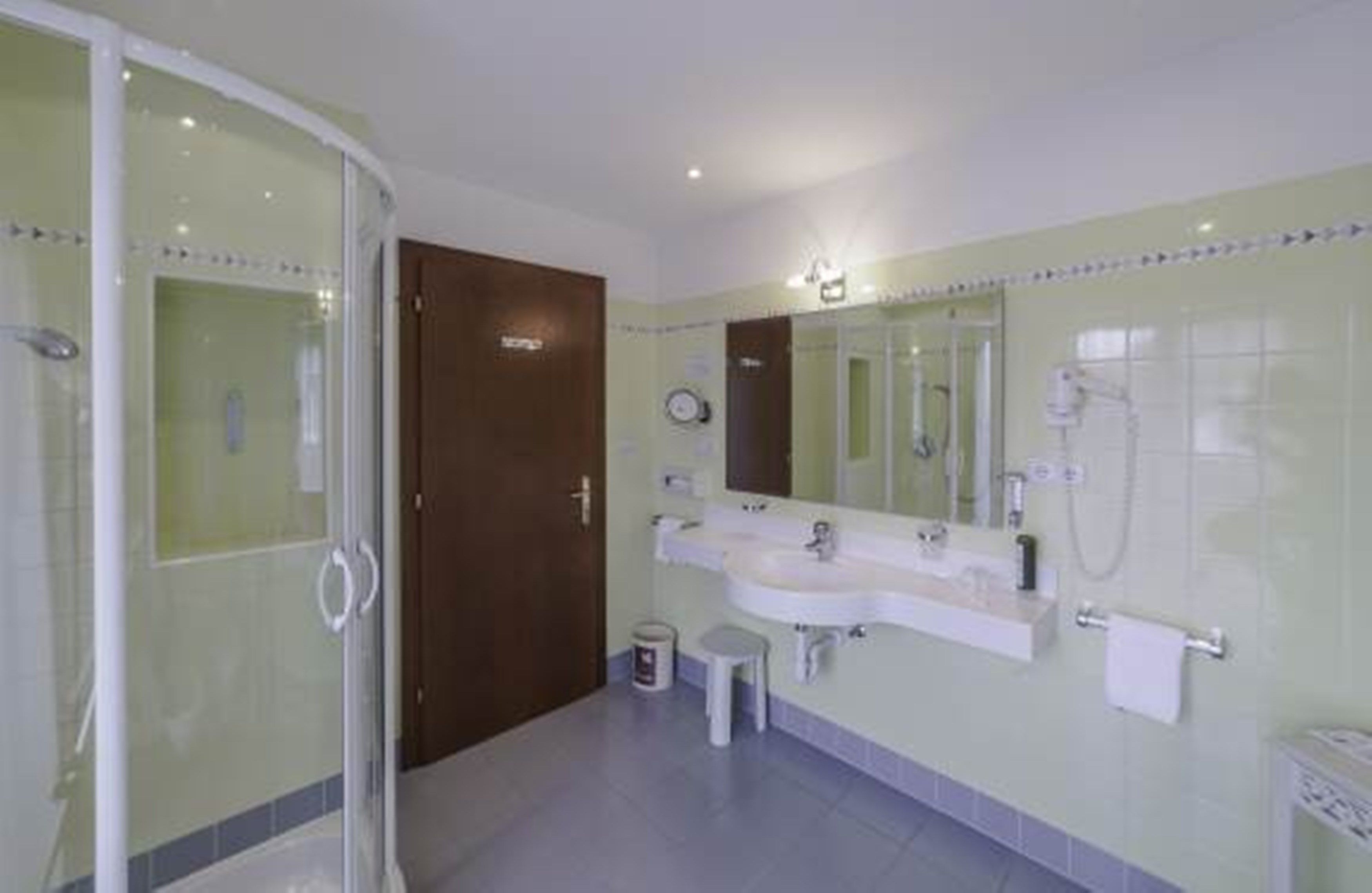 Un baño con cabina de ducha de vidrio, tocador doble y un espejo grande.