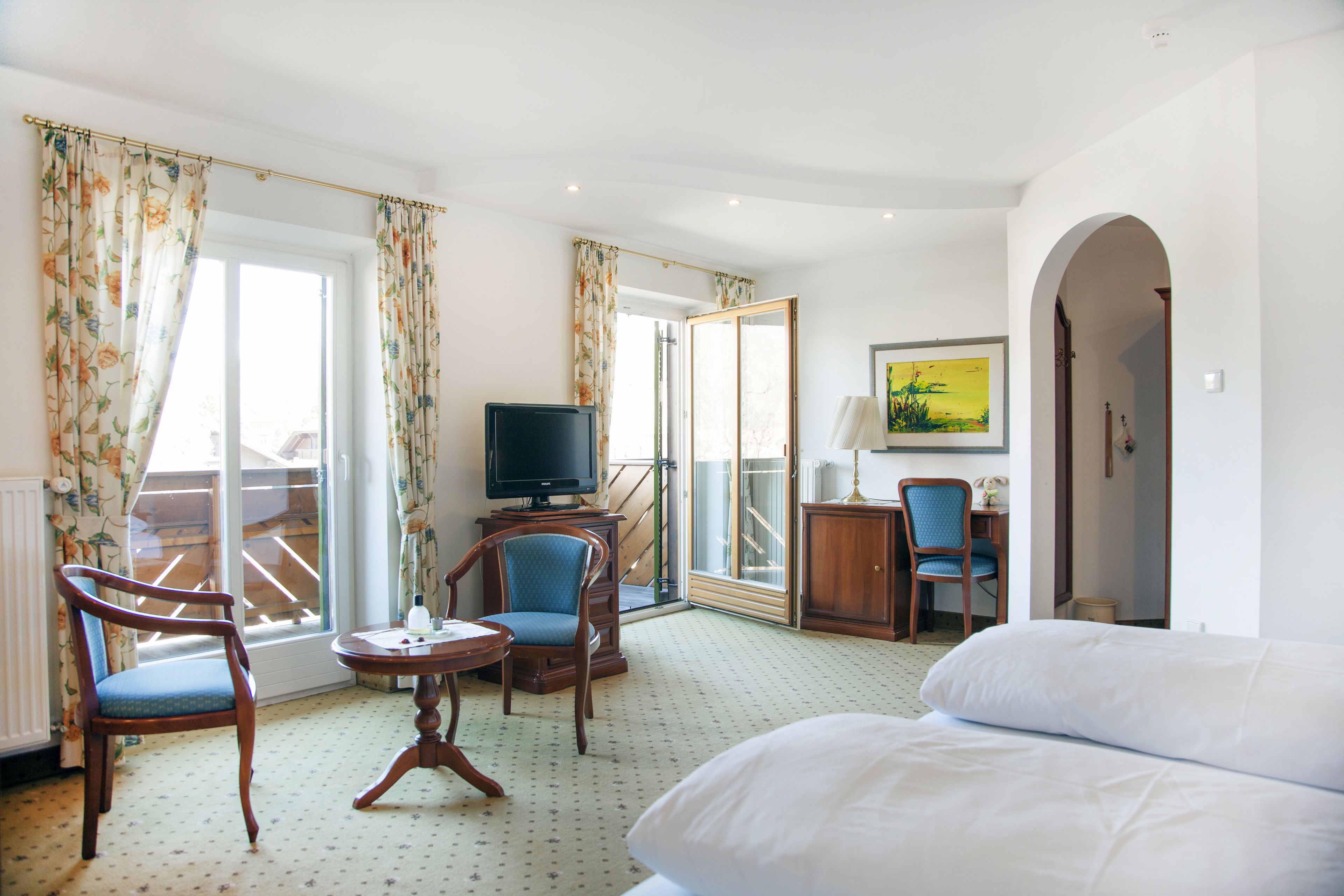 Une chambre d’hôtel comprenant un lit, une télévision, un bureau avec une chaise et une vue sur l’extérieur grâce à une porte coulissante.
