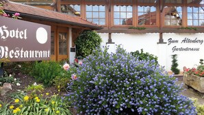 A hotel with a sign reading "Hotel Restaurant" and a garden with purple flowers and yellow blooms. - Hotel Altenberg (Baden-Baden)