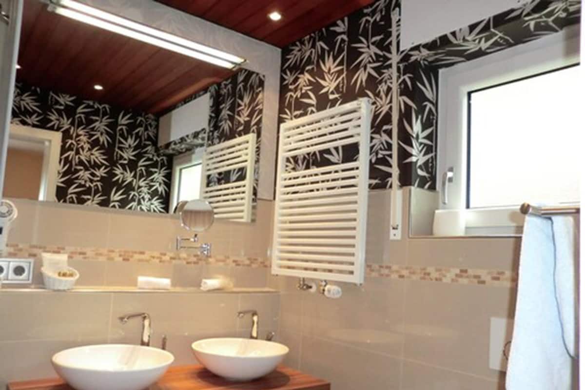 A bathroom with two white sinks, a wooden countertop, a mirror, and a towel rack.
