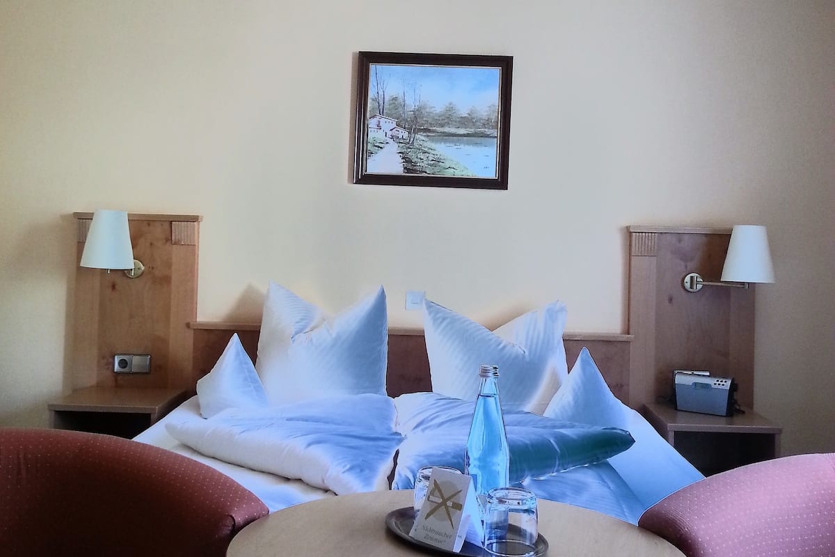 A hotel room with a bed, two nightstands, a table, and two chairs.