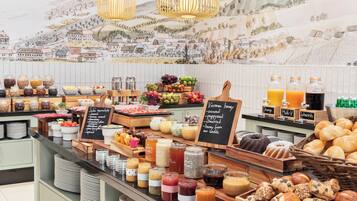 Un bufé con diversos alimentos y bebidas, como frutas, pasteles y salsas.