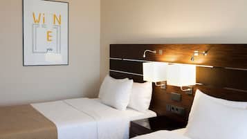 Een hotelkamer met twee bedden, een houten hoofdbord, bedlampjes en een lijst met kunstwerk aan de muur.