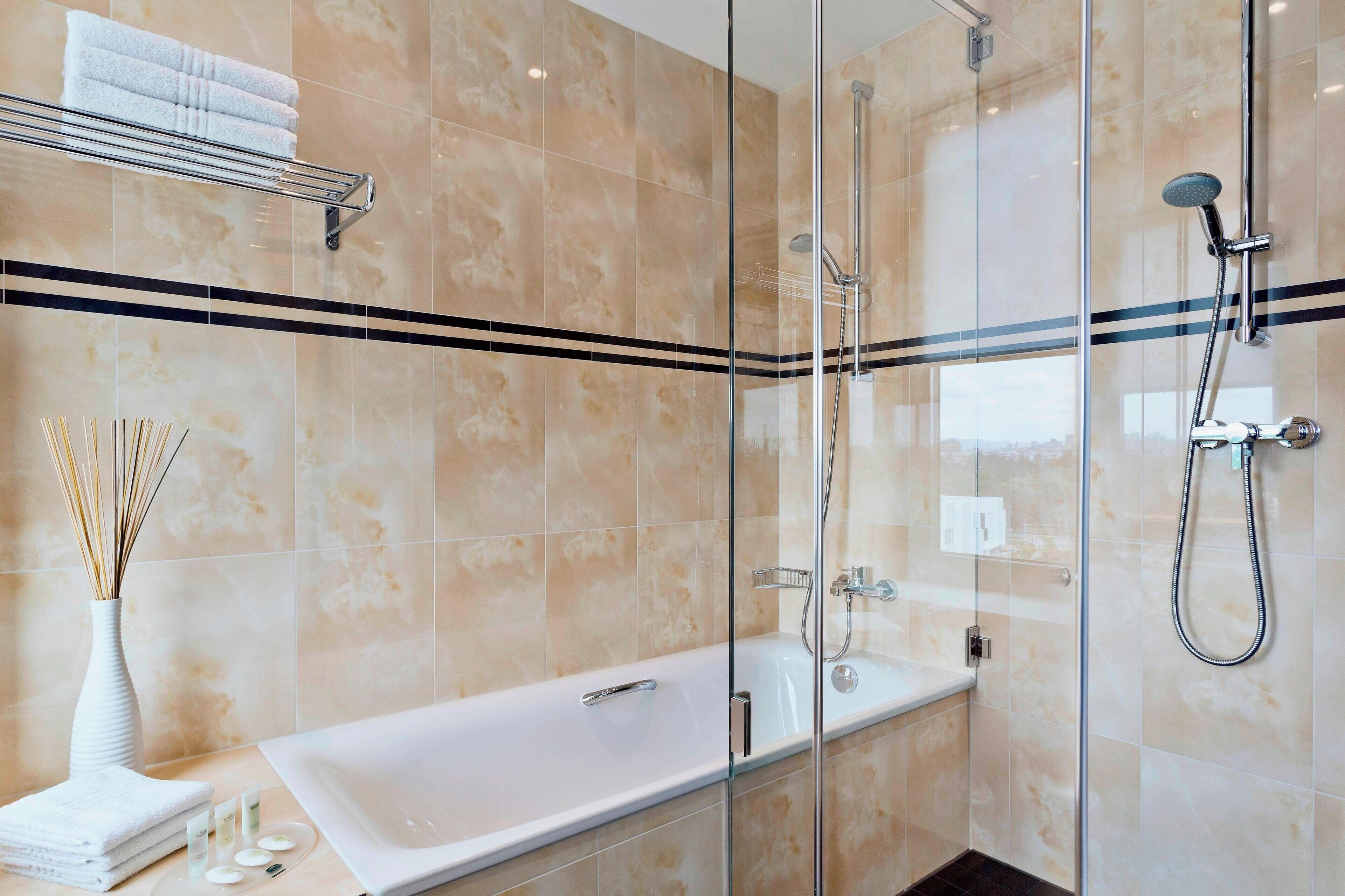 Uma casa de banho moderna com chuveiro de vidro, banheira e porta-toalhas.