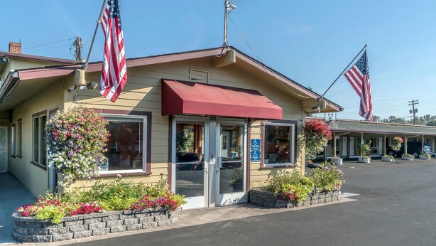 Um motel com duas bandeiras americanas, um toldo vermelho e um estacionamento.