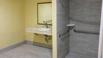 A bathroom with a sink, mirror, and shower area.