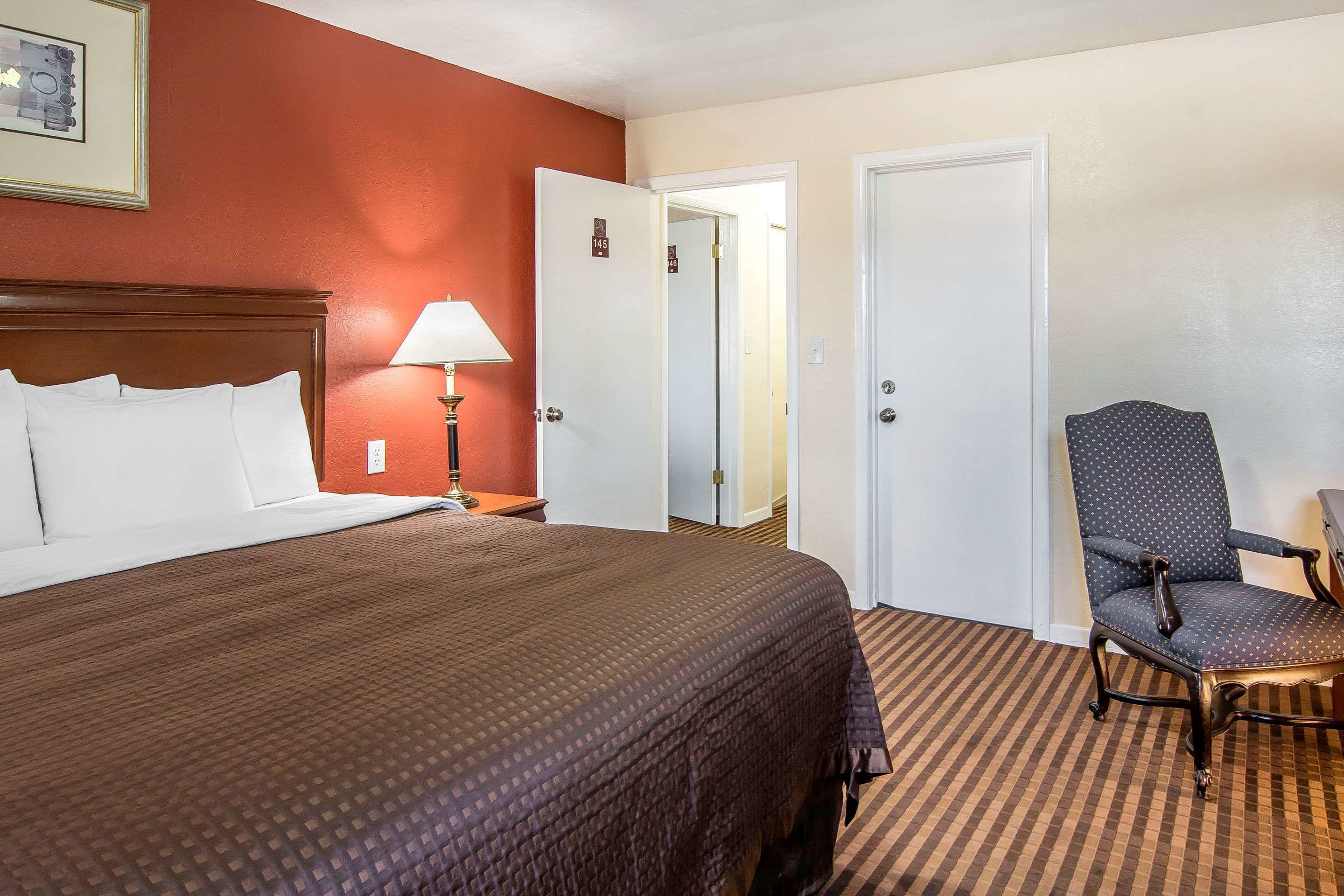 Een hotelkamer met een groot bed, een stoel en twee deuren.