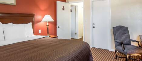 Een hotelkamer met een groot bed, een stoel en twee deuren.