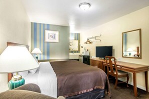 A hotel room with a bed, desk, chair, TV, and a mirror.