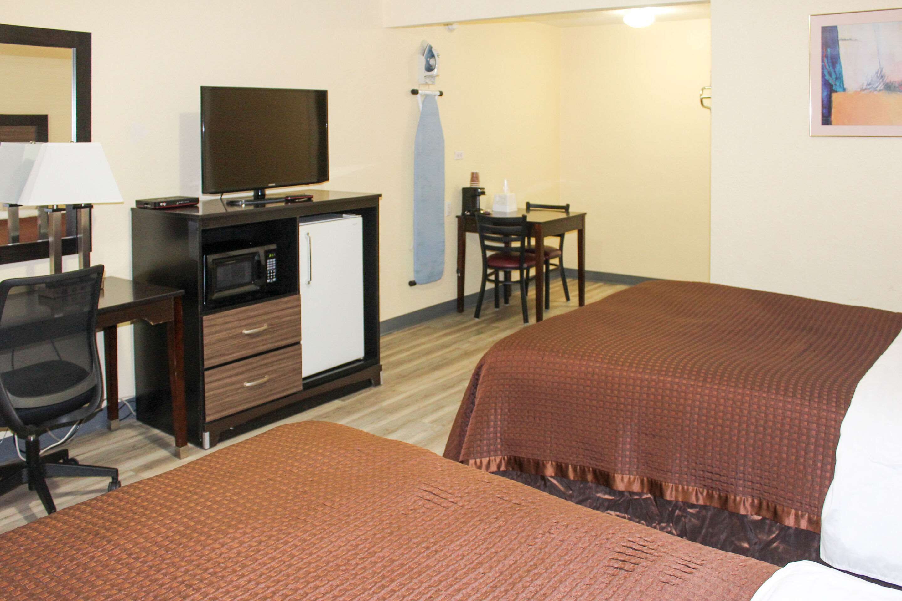 Hotelkamer met een bed, een bureau met een televisie, een magnetron, een stoel en een kleine tafel.