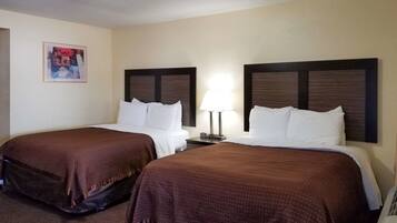 A hotel room with two beds, each with a brown blanket, a bedside table with a lamp, and a framed picture on the wall.