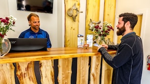 A reception desk with wooden slats, a laptop, and two vases with flowers. - Alaska Glacier Lodge (Palmer)