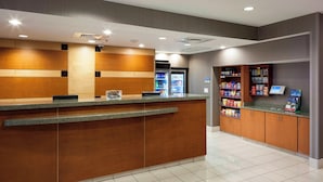 Ein Hotel-Empfangsbereich mit einem Holzbüro, einer Selbstbedienungs-Kiosk und einem Kühlregal.