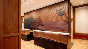A reception desk with a wooden finish, a large animal silhouette, and a wall-mounted clock.