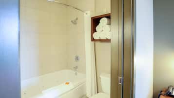 A bathroom with a bathtub, toilet, and a shelf with towels.