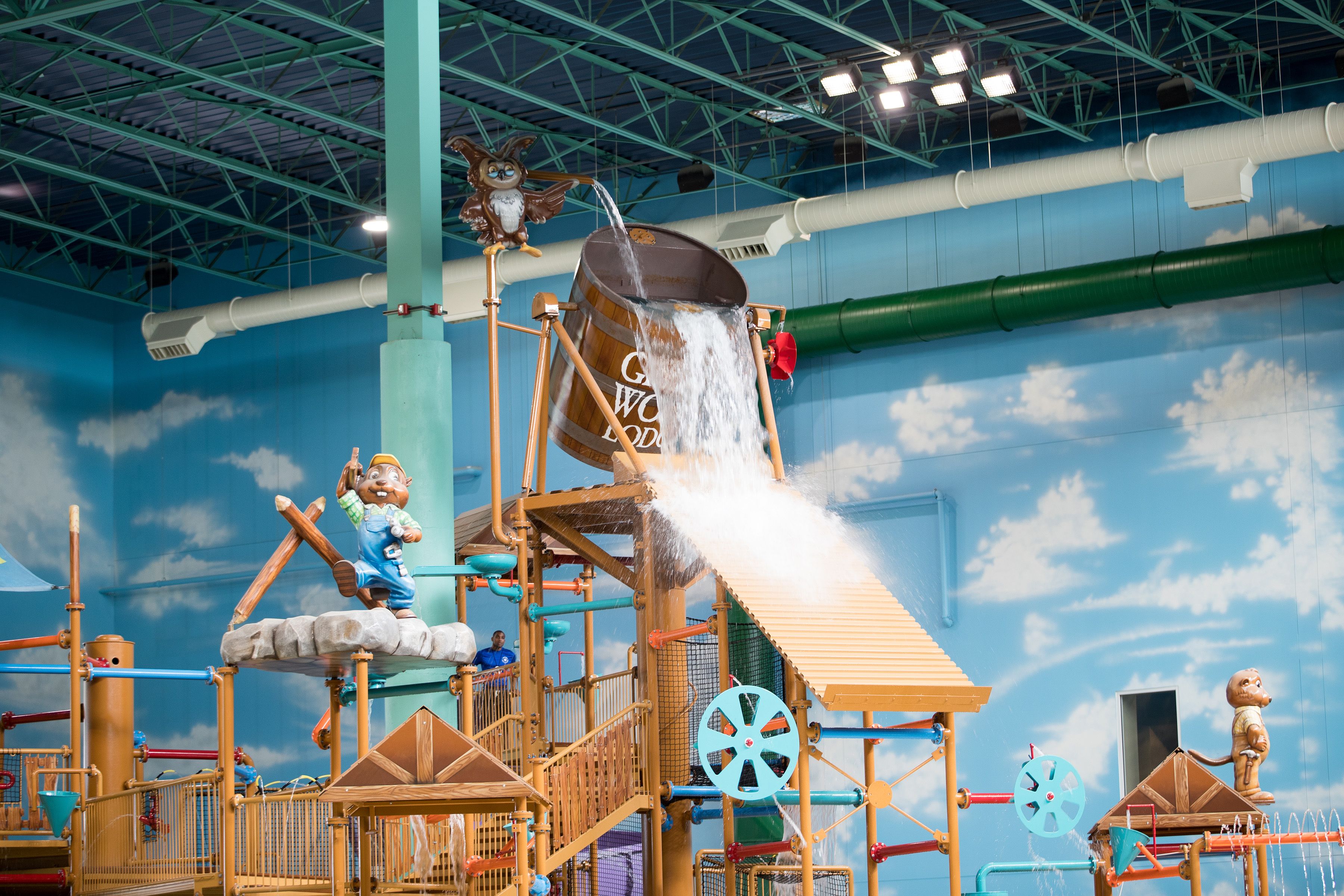 A water play area with a wooden structure, a bucket, and a figure of a bear.