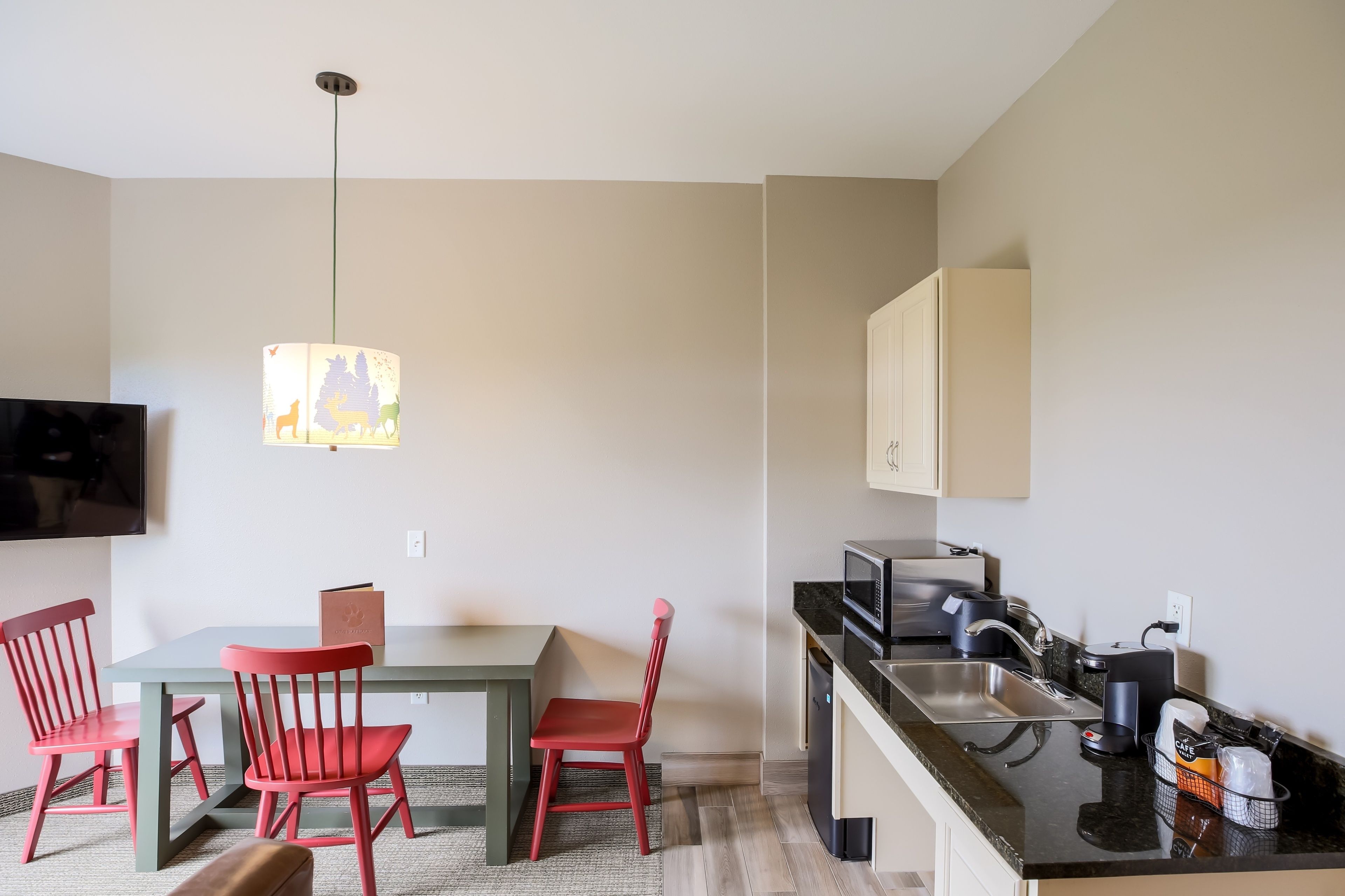 A compact kitchen with a dining area, including a table, chairs, and a pendant light.