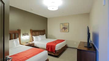 A hotel room with two beds, a desk, a television, and a painting on the wall.
