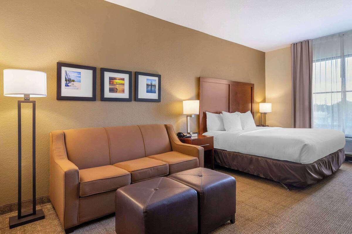 Ein Hotelzimmer mit Bett, einer Couch, einem Couchtisch und gerahmten Bildern an der Wand.