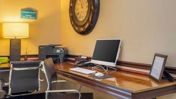 Escritorio de centro de negocios con computadora, teclado, ratón y un reloj en la pared.