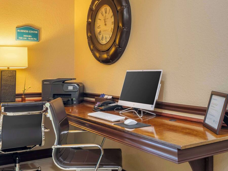 Escritorio de centro de negocios con computadora, teclado, ratón y un reloj en la pared.