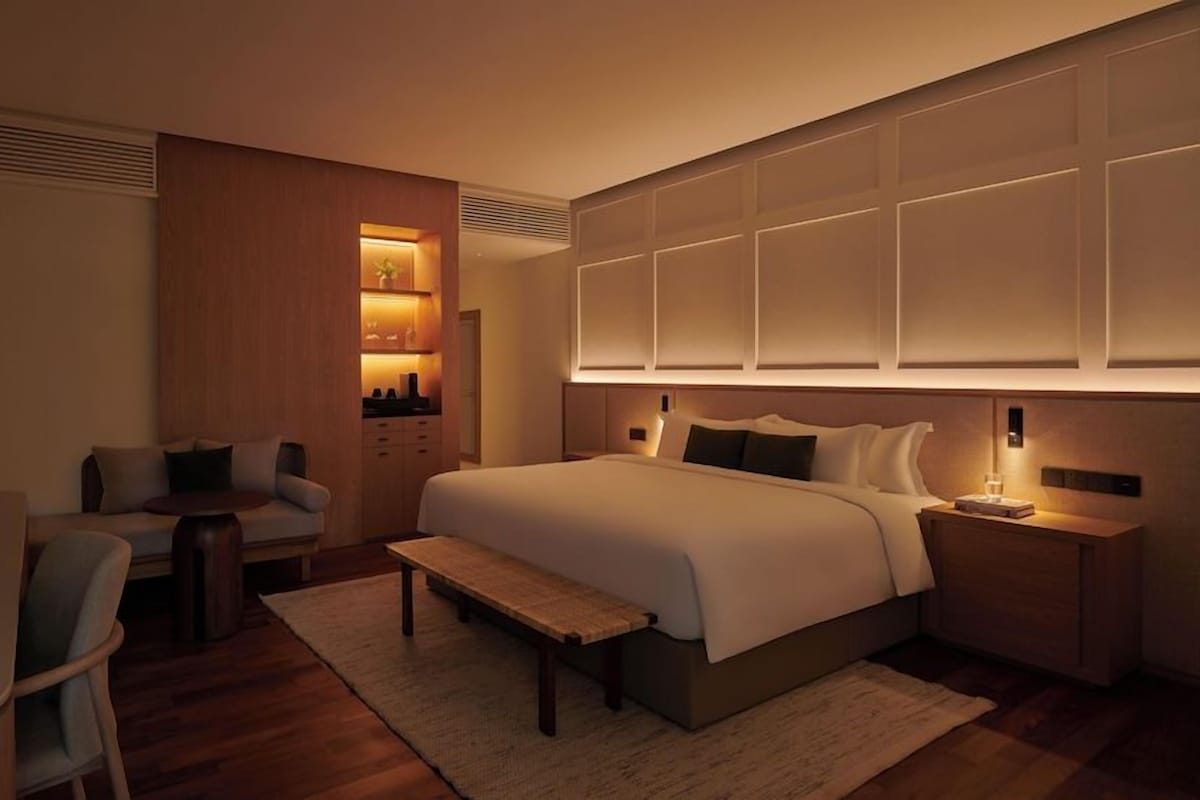 A modern hotel room with a large bed, bedside tables, a desk, and a chair.