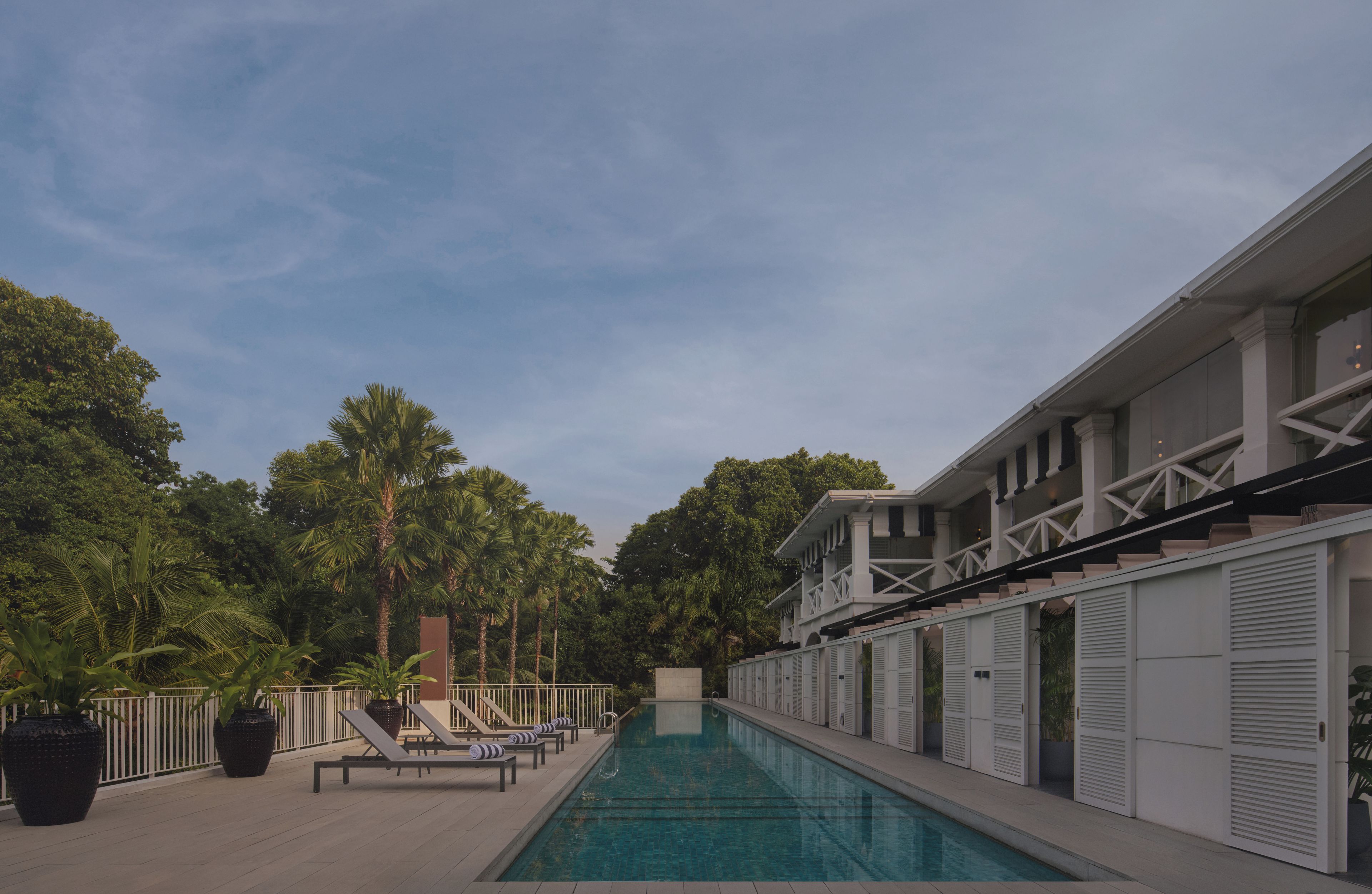 A swimming pool with lounge chairs and a building with shutters.