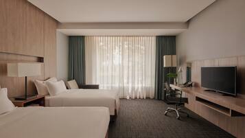 A hotel room with two beds, a desk with a TV, a lamp, and a chair.