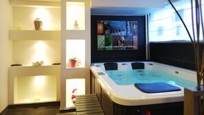 Un cuarto de spa con un jacuzzi, repisas con objetos decorativos y una pared con un cartel.