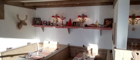 A cozy restaurant with wooden beams, red and white checkered tablecloths, and a variety of decorations including a moose head, a 'Picture' sign, and wall-mounted lights.