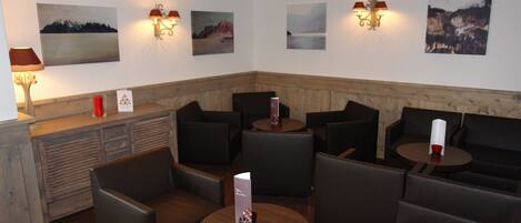 A cozy lounge area with leather seating, wooden tables, and wall-mounted artwork.
