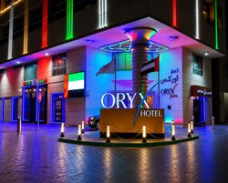 Fachada de un hotel con un letrero llamativo, una bandera y un despliegue de luces de neón.
