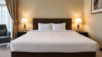 Habitación de hotel con una cama grande, dos lámparas de noche, un teléfono y una silla.