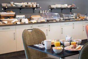 Un bufé de desayuno con diversos alimentos y bebidas sobre una mesa.
