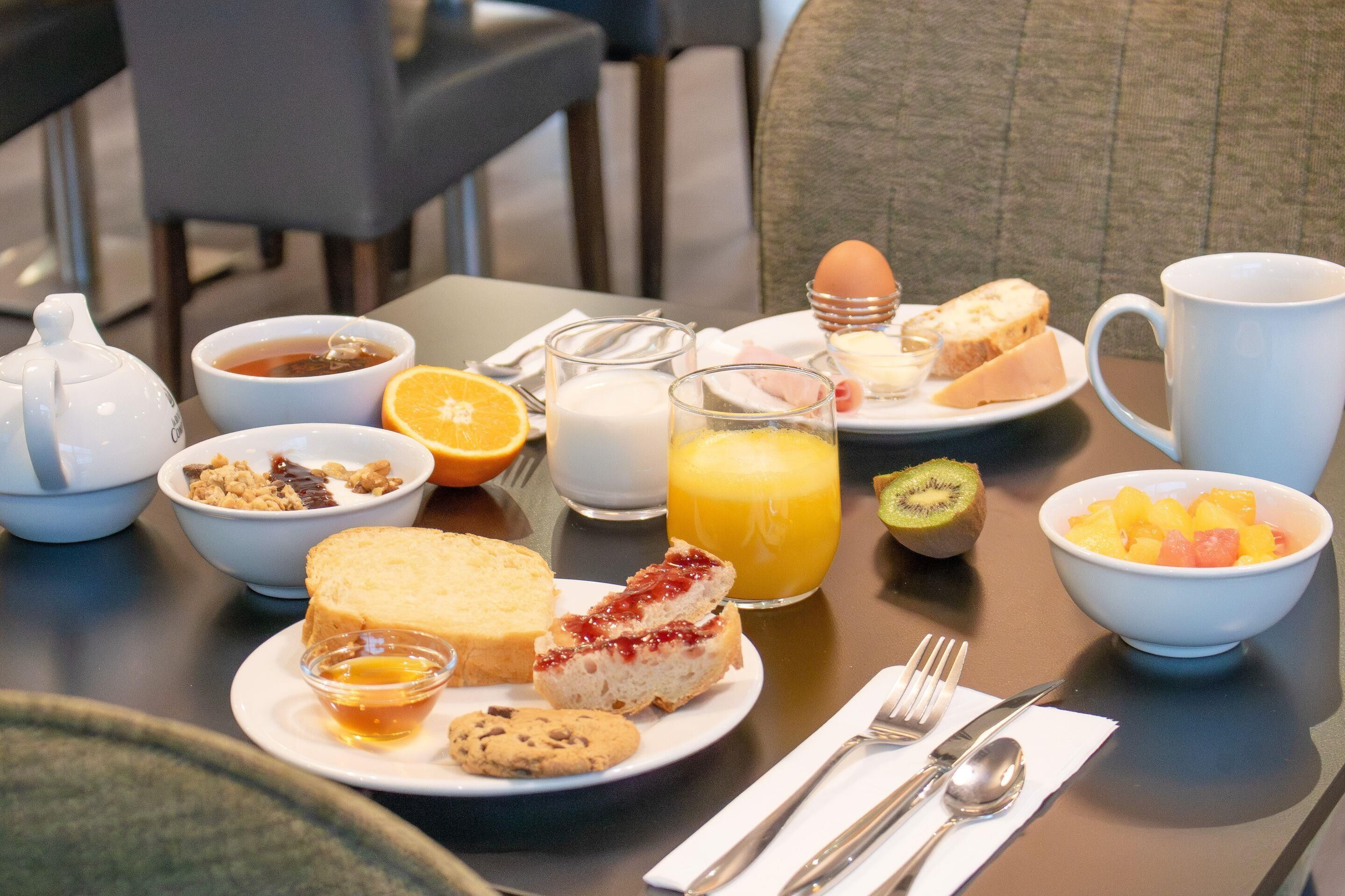 A breakfast table with various food items, including toast, fruit, and beverages.