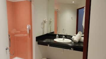 A bathroom with a glass-enclosed shower, a sink with a mirror above it, and a towel rack.