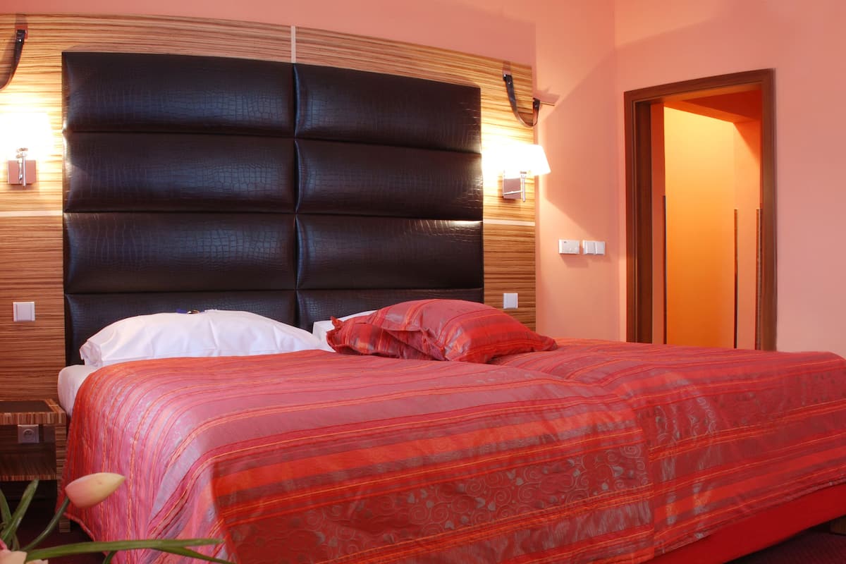 Een hotelkamer met een groot bed, een houten hoofdeinde en een rode sprei.