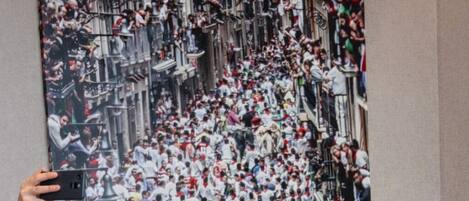 Un grupo de personas vestidas de blanco y rojo posan frente a un mural grande que muestra una escena concurrida.